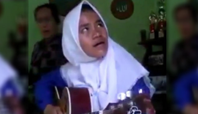 Wanita bernyanyi sambil bermain gitar.