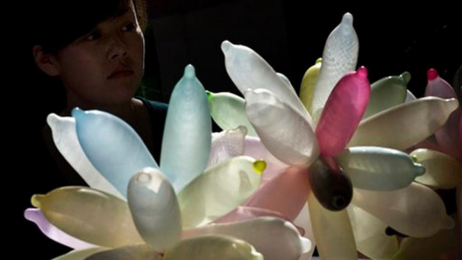 Seorang perempuan menatap rangkaian kondom di suatu pameran di Beijing, China