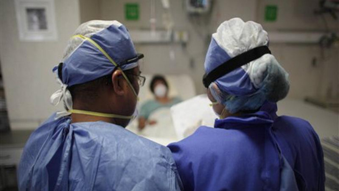 Dua staf medis di Meksiko memantau kondisi seorang pasien flu babi