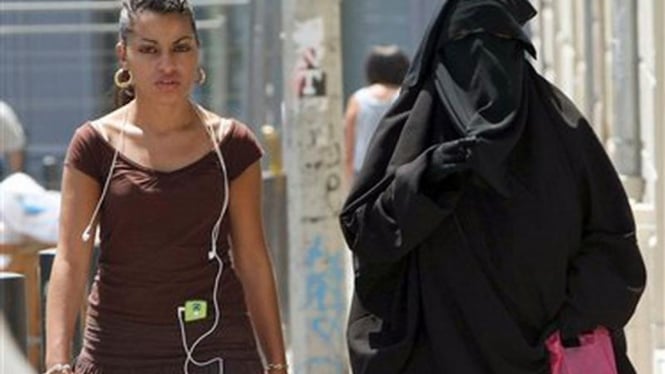 Seorang perempuan di Prancis berjalan dengan mengenakan burka (kanan)
