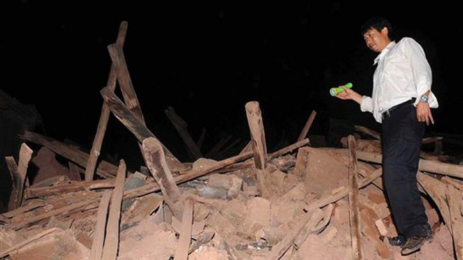 Seorang pria berdiri di atas reruntuhan akibat gempa di provinsi Yunnan, China
