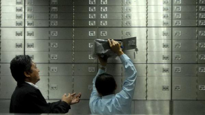 Petugas membatu nasabah menurunkan barang dari safe deposit box