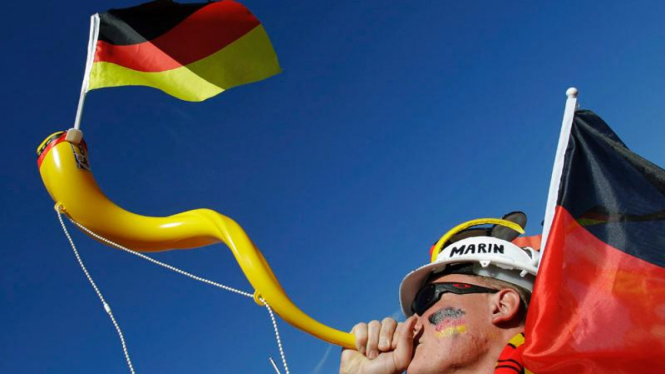 Suporter Jerman sedang meniup vuvuzela.