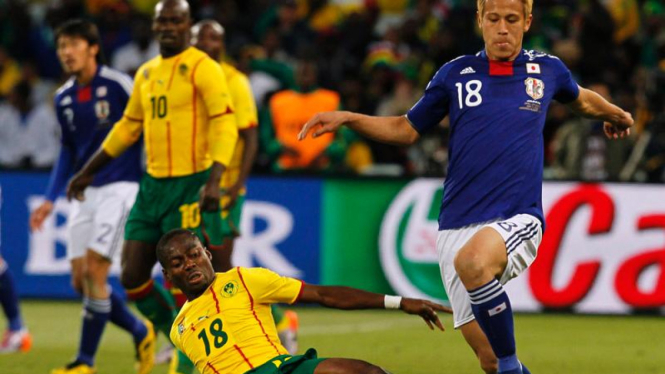Pemain Jepang, Keisuke Honda dijegal oleh pemain Kamerun.