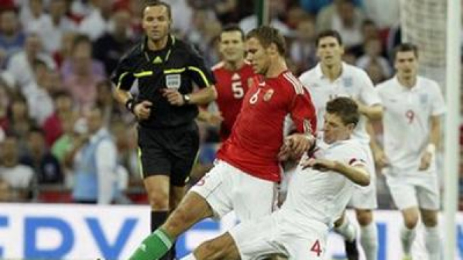 Steven Gerrard menghadang Krisztian Vadocz (Hongaria/merah)