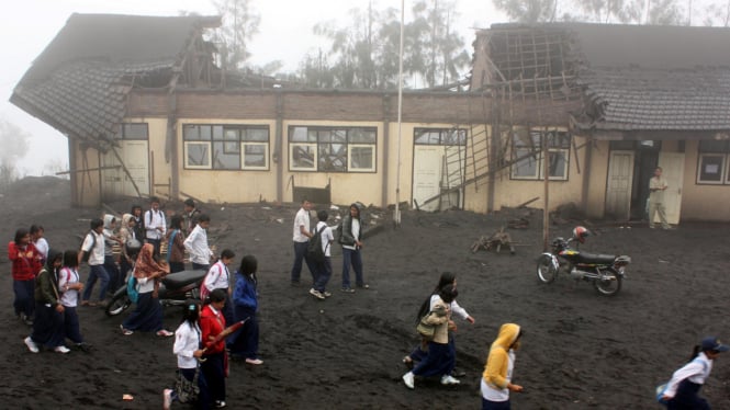 Para siswa melewati sekolah yang rusak karena abu vulkanik dari Bromo
