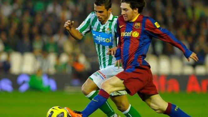 Lionel Messi berebut bola dengan pemain Real Betis