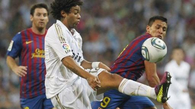 Pemain Real Madrid Marcelo (putih) diapit pemain Barcelona
