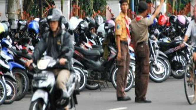 Anggota Pramuka sedang membantu mengatur lalulintas