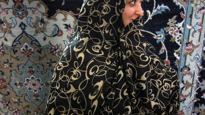 Wanita Iran berjalan di depan karpet Persia