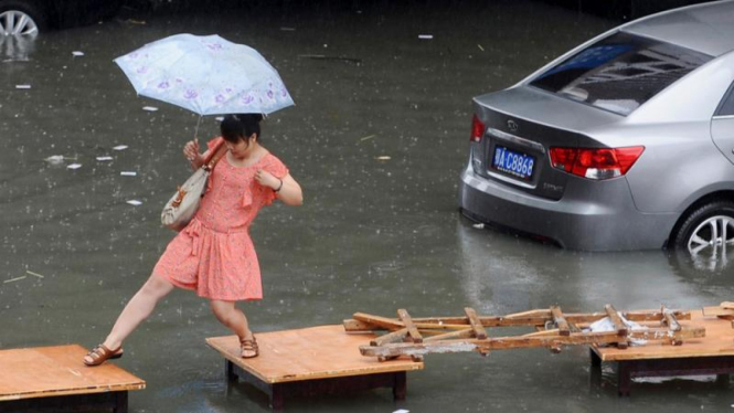 Wanita berjalan di tengah banjir di China