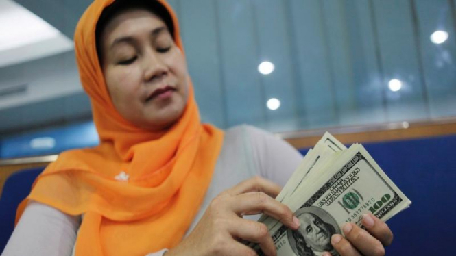 Seorang perempuan menghitung uang kertas dolar AS 