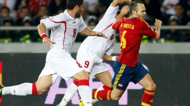 Pemain timnas Spanyol, Andres Iniesta, dikawal dua pemain Georgia.