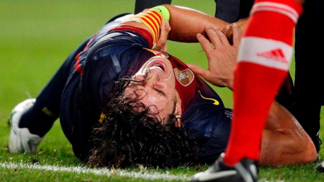 Kapten Barcelona, Carles Puyol, meringis kesakitan saat menghadapi Benfica
