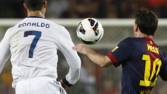 Cristiano Ronaldo (kiri) berebut bola dengan Lionel Messi