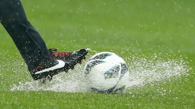 Pemain Inggris coba menendang bola di lapangan yang banjir