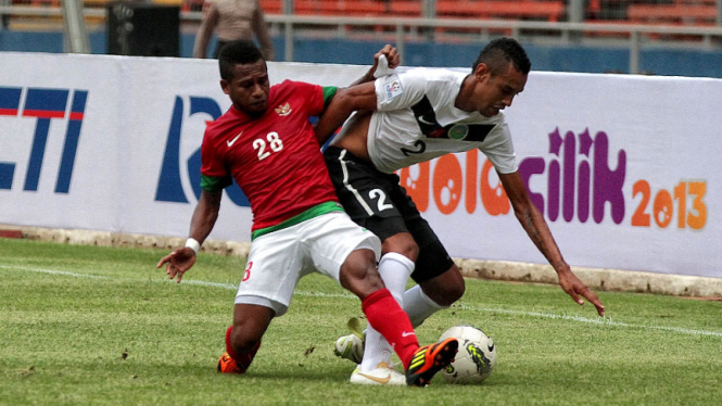 Okto Maniani (kiri) saat melewati hadangan para pemain Timor Leste, (14/11/2012).