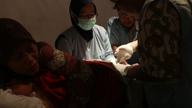 Seorang ibu coba menenangkan anaknya yang tengah disunat tim dokter.