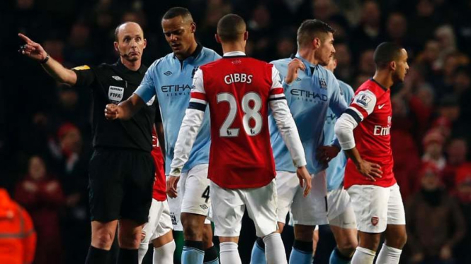 Wasit Mike Dean (kiri) meminta Vincent Kompany meninggalkan lapangan