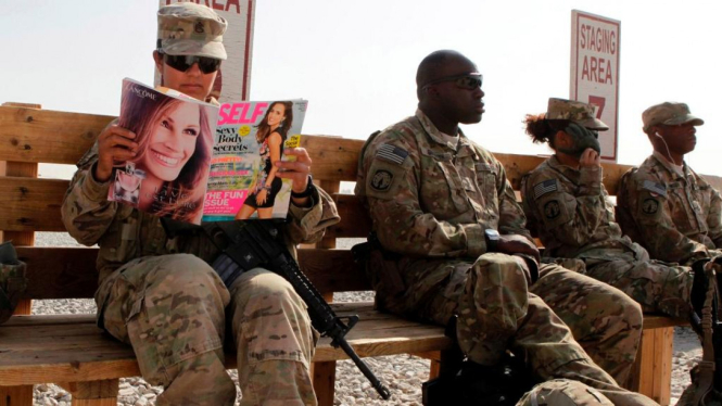 Seorang perempuan prajurit AS membaca majalah wanita