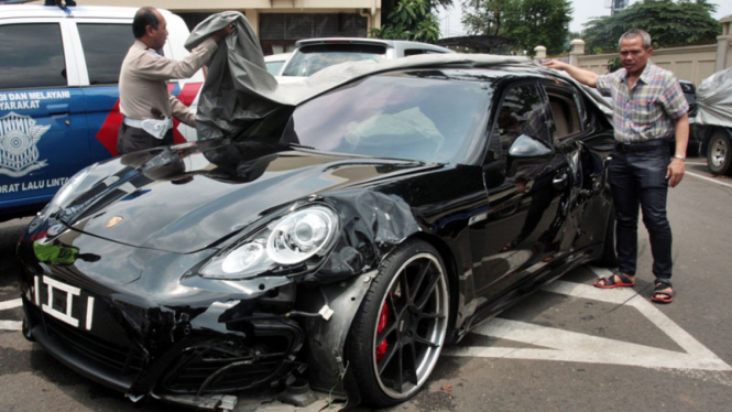 Polisi menutupi mobil mewah Porsche Panamera yang ringsek