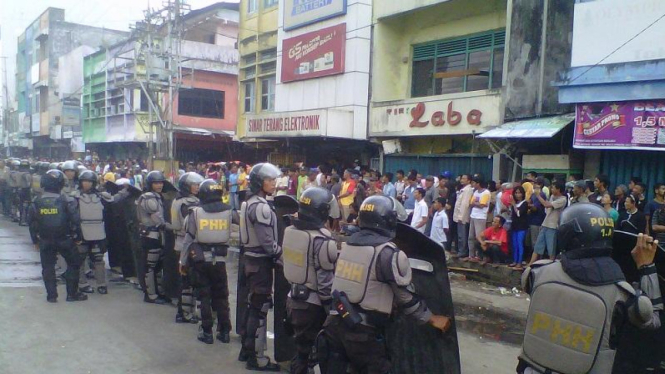 Kebakaran Palembang dipicu aksi massa. Polisi berjaga dekat lokasi kebakaran.