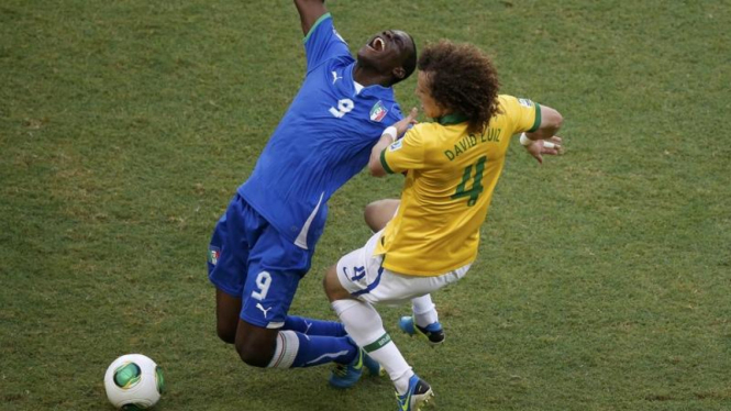 Pemain Italia, Mario Balotelli, saat dilanggar David Luiz