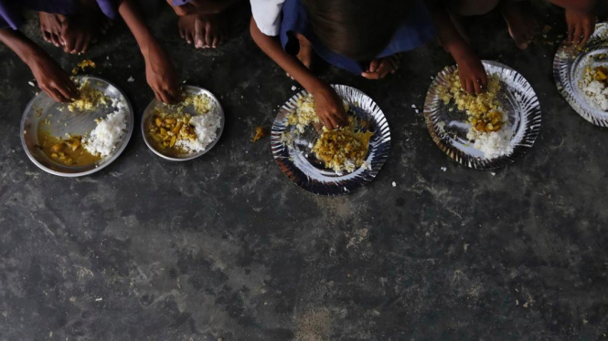 Para murid sekolah negeri di India menikmati makan siang gratis