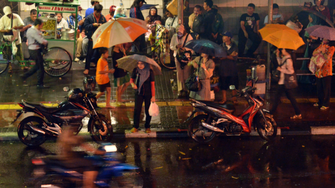 Para pekerja menggunakan payung saat hujan mengguyur Jakarta beberapa waktu lalu.