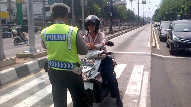 Seorang pengendara motor yang masuk jalur busway.