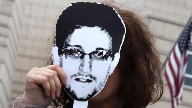 Seorang pemrotes di Berlin tunjukkan topeng bergambar Edward Snowden