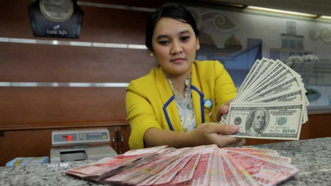 Seorang petugas bank menunjukkan uang kertas dolar AS dan rupiah beberapa waktu lalu.