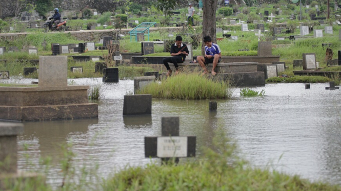 Ilustrasi/Warga Memancing Ikan di area pemakaman yang terendam banjir