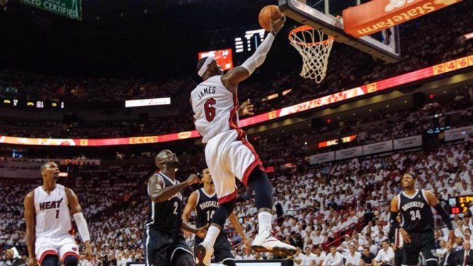 Pemain Miami Heat, LeBron James, memasukan bola