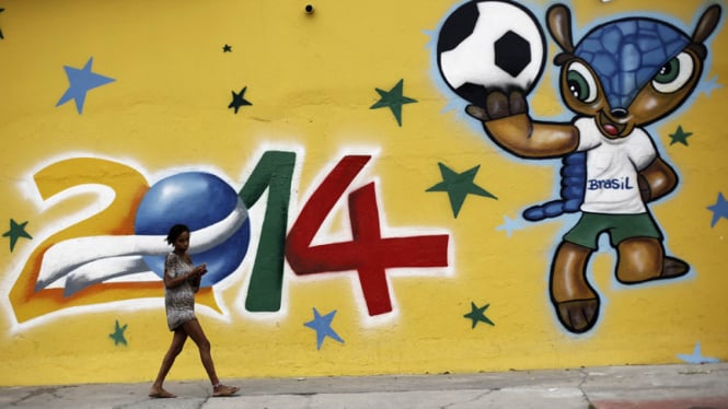 Seorang wanita berjalan di depan dinding bergambar maskot resmi Piala Dunia
