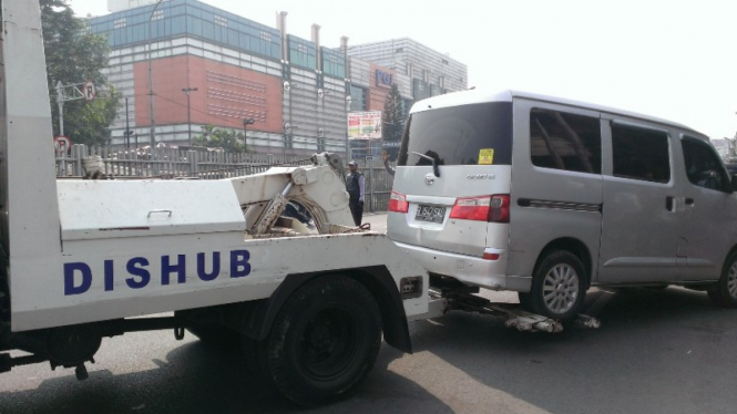 Petugas Dishub menderek mobil dalam operasi parkir liar di Jatinegara. 