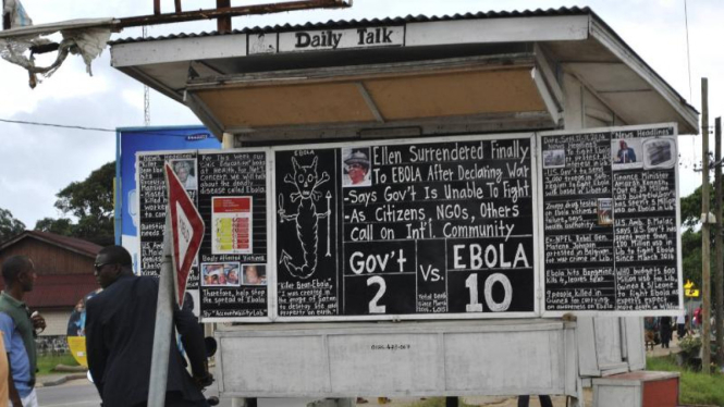 Warga membaca berita tentang epidemi Ebola di Liberia.