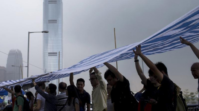 Pemrotes Hong Kong berteduh dari hujan menggunakan terpal, 3 Oktober.
