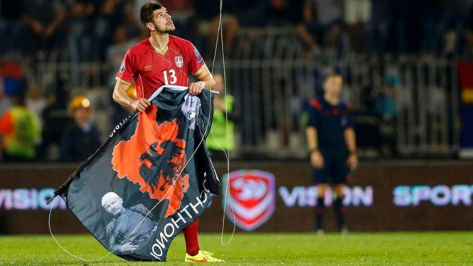 Pemain Serbia, Stefan Mitrovic, saat menarik turun bendera Albania