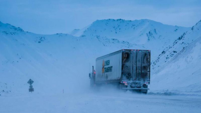 Truk sedang melintasi jalanan yang tertutup salju di Alaska, Amerika Serikat