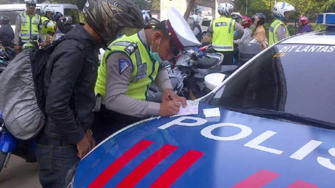 Seorang petugas kepolisian tengah melakukan penilangan terhadap pengendara yang melintas di Jalan Rasuna Said Jakarta Selatan, Kamis 27 November 2014