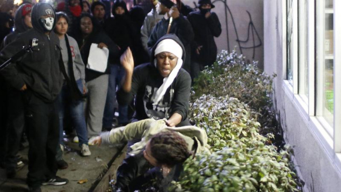 Pemrotes memukul pria, yang berusaha mencegah perusakan toko saat demonstrasi.
