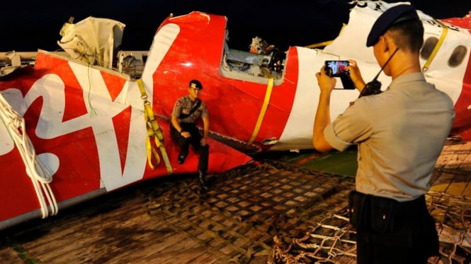 Personel polisi berfoto di depan bangka pesawat AirAsia QZ8501