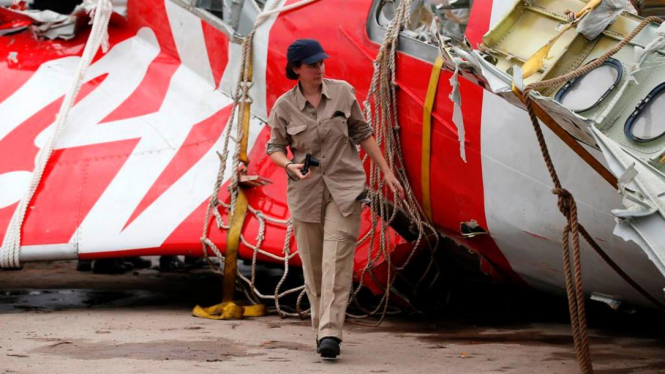 Seorang investigator meneliti potongan ekor pesawat AirAsia.