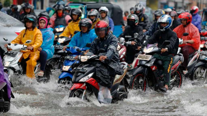 Ilustrasi/Pemotor melintasi banjir Jakarta
