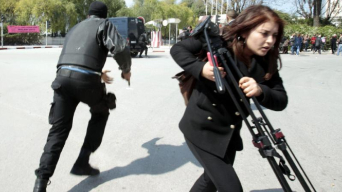 Polisi dan jurnalis berlari di luar gedung parlemen Tunisia
