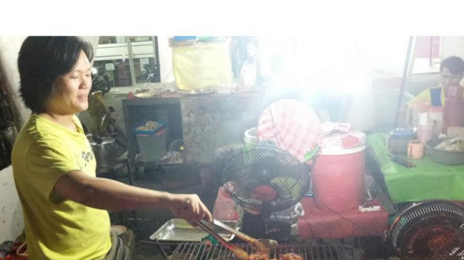 Pengusaha UKM ayam bakar sedang melayani pelanggannya.