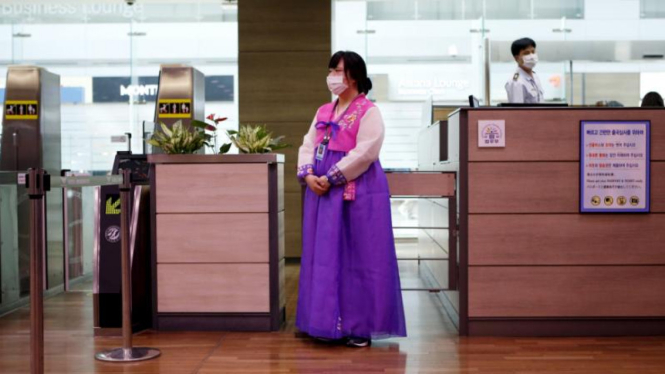 Wanita dengan baju tradisional Korsel di bandara Incheon mengenakan masker.