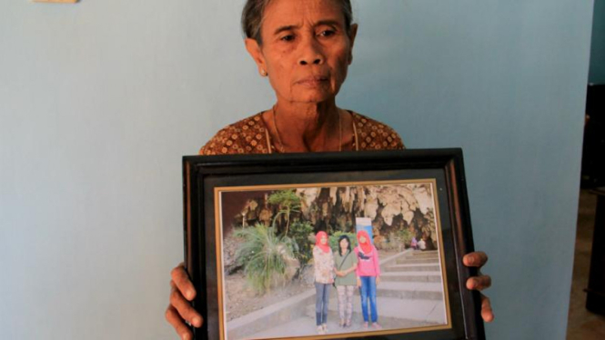 Suyati 65 tahun, menunjukkan foto keluarganya yang tewas