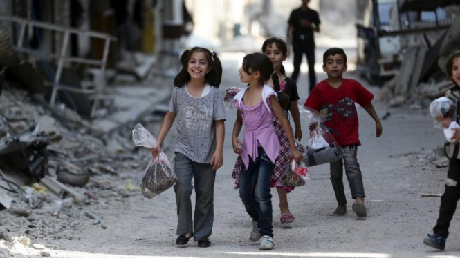 Anak-anak membawa sekantung baju baru untuk lebaran di Suriah.